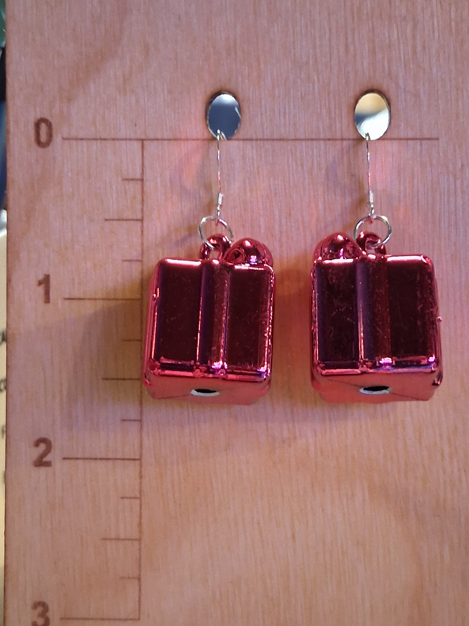 Pink rectangular present earrings on a wooden surface with a ruler for scale.