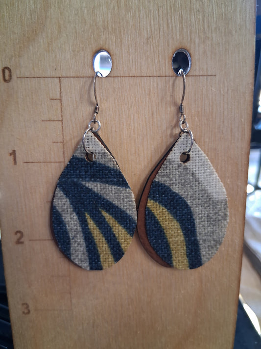 Pair of earrings with fabric in front of a pleather back on a wooden surface with a ruler for scale.