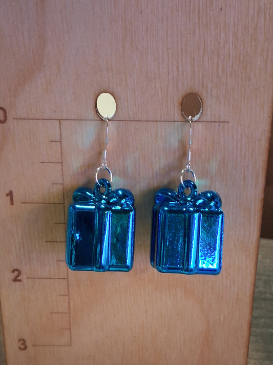 Sapphire blue Christmas present charm earrings with silver-tone ear wires displayed on a wooden jewelry stand. Blue rectangular present earrings on a wooden surface with a ruler for scale.