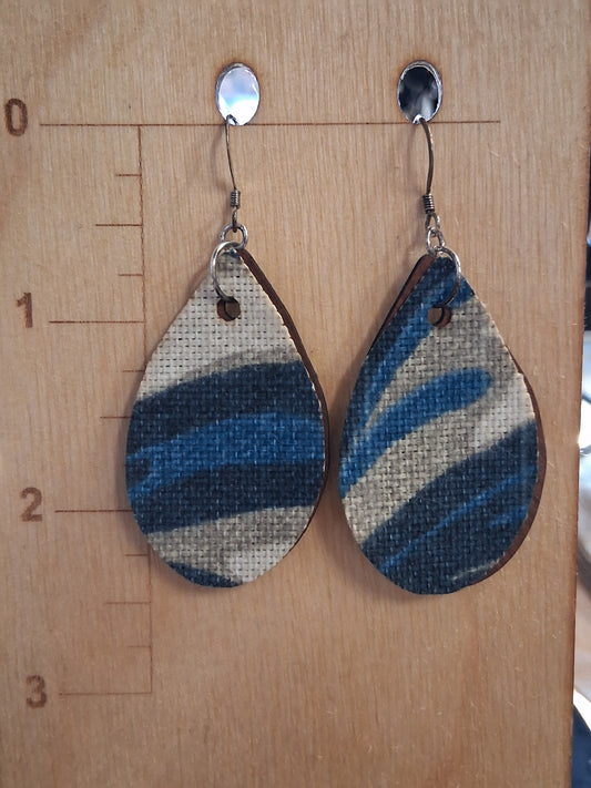 Pair of earrings with fabric in front of a pleather back on a wooden surface with a ruler for scale.