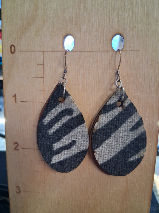 Pair of earrings with fabric in front of a pleather back on a wooden surface with a ruler for scale.