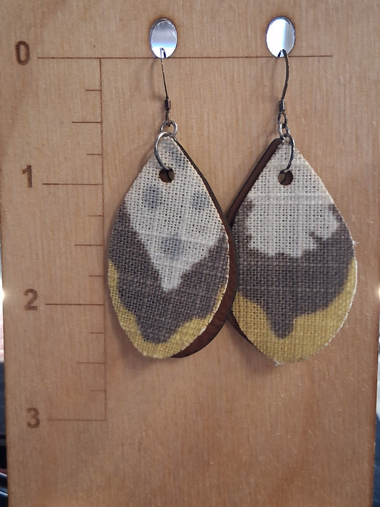 Pair of earrings with fabric in front of a pleather back on a wooden surface with a ruler for scale.